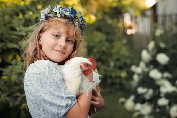 Dívka chová slepici v náručí na statku